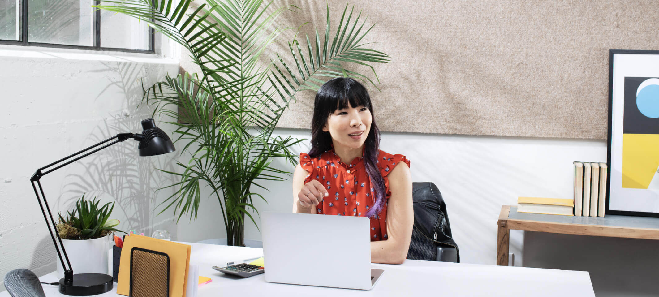 A woman sitting at a white desk looking at something across the room